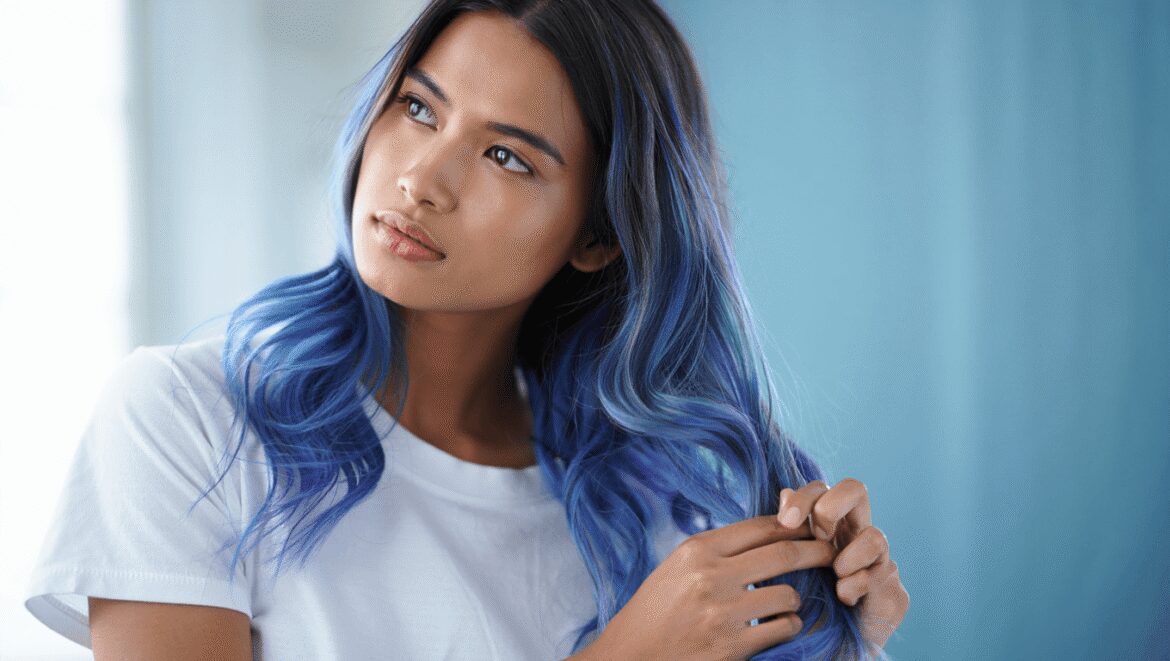 Une personne se lave les cheveux sous la douche avec du shampoing bleu pour neutraliser les reflets indésirables.