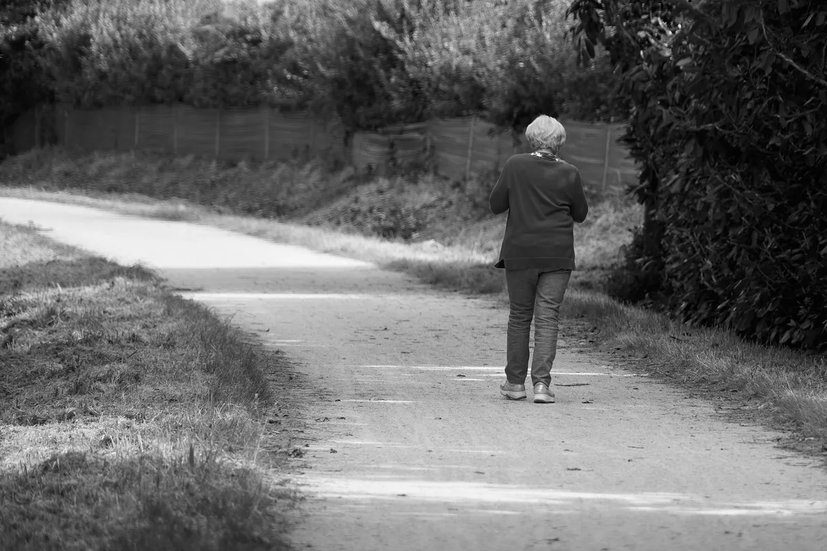 Personne d'âge mûr marchant à l'extérieur, illustrant une activité physique de faible intensité.