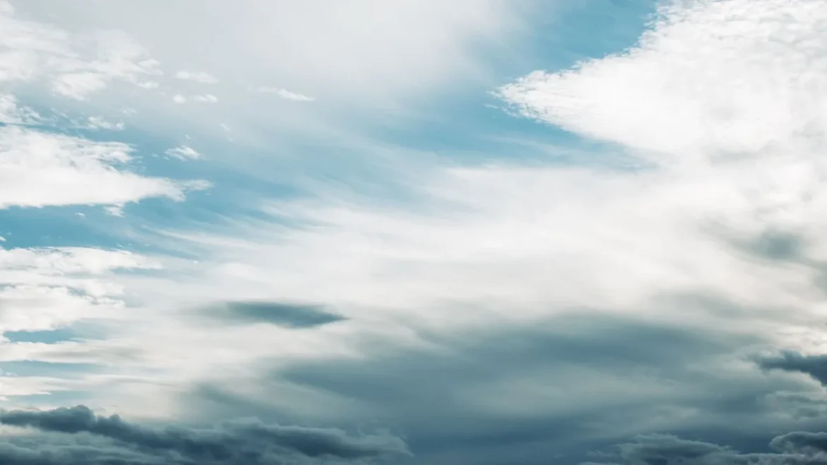 Mains appliquant un spray de protection solaire sous un ciel nuageux