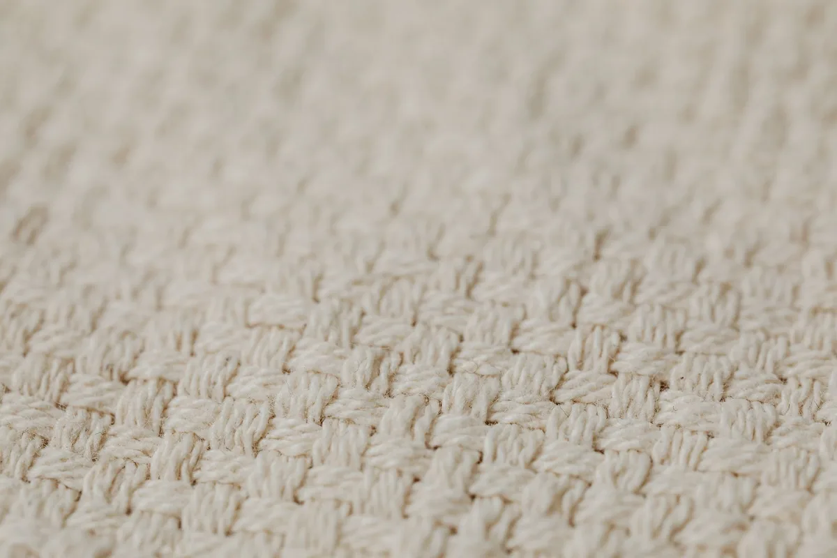 Détail de tissus naturels en lin et coton avec motif vichy, montrant la qualité des fibres.