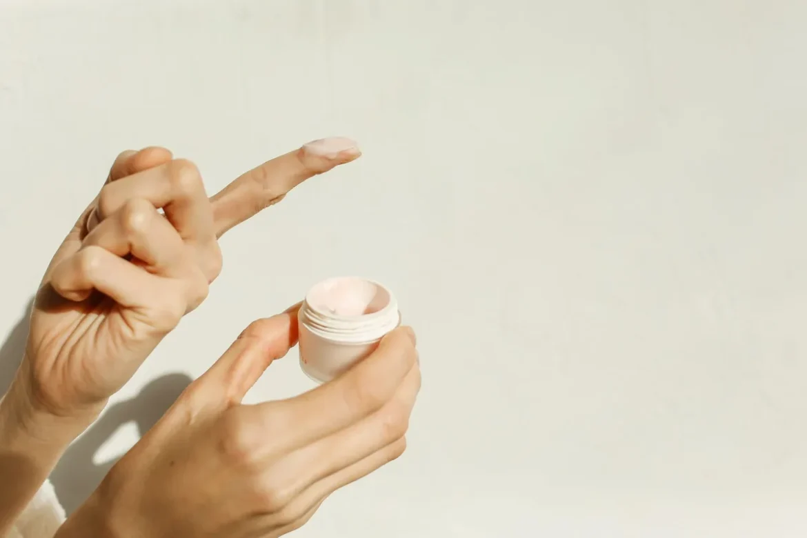 Personne appliquant un déodorant crème sur son aisselle dans une salle de bain bien éclairée
