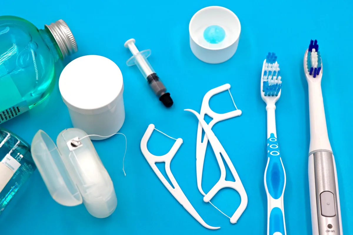 Personne se brossant les dents avec une brosse à dents et du fil dentaire