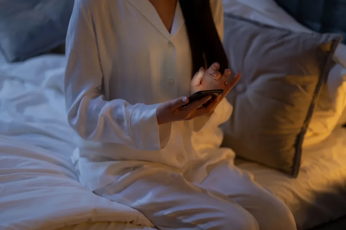 Personne allongée dans un lit la nuit, main sur la poitrine, expression d'inconfort due au reflux acide.
