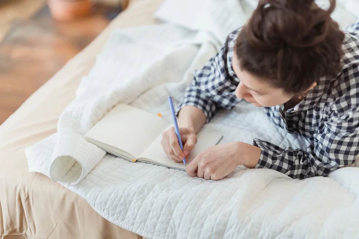 Femme tenant un journal pour noter la fréquence et les contextes des bouffées de chaleur