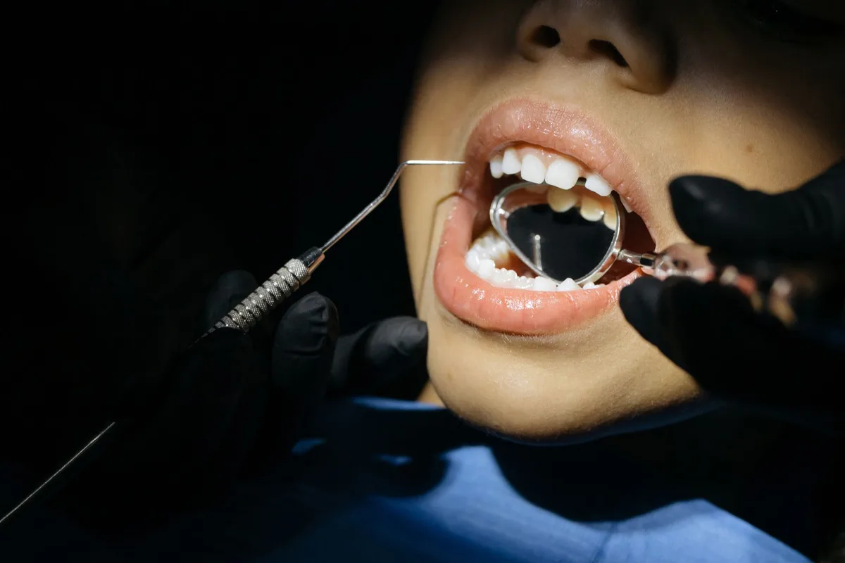 Dentiste pédiatrique examinant les dents d'un enfant avec des instruments adaptés