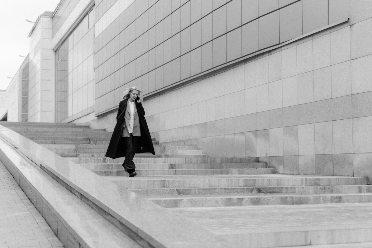 Femme portant un long manteau droit qui crée une ligne verticale allongeante