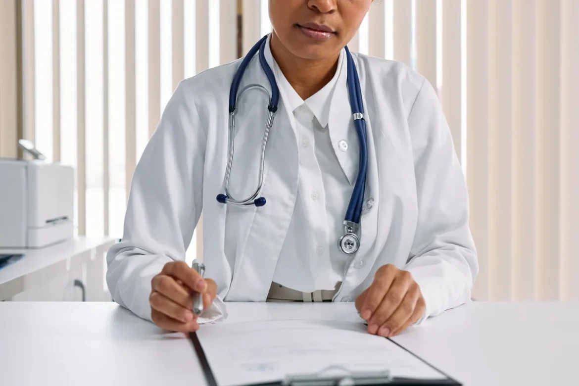 Patient en consultation avec un praticien dans un cabinet médical moderne, documents et stylo sur le bureau