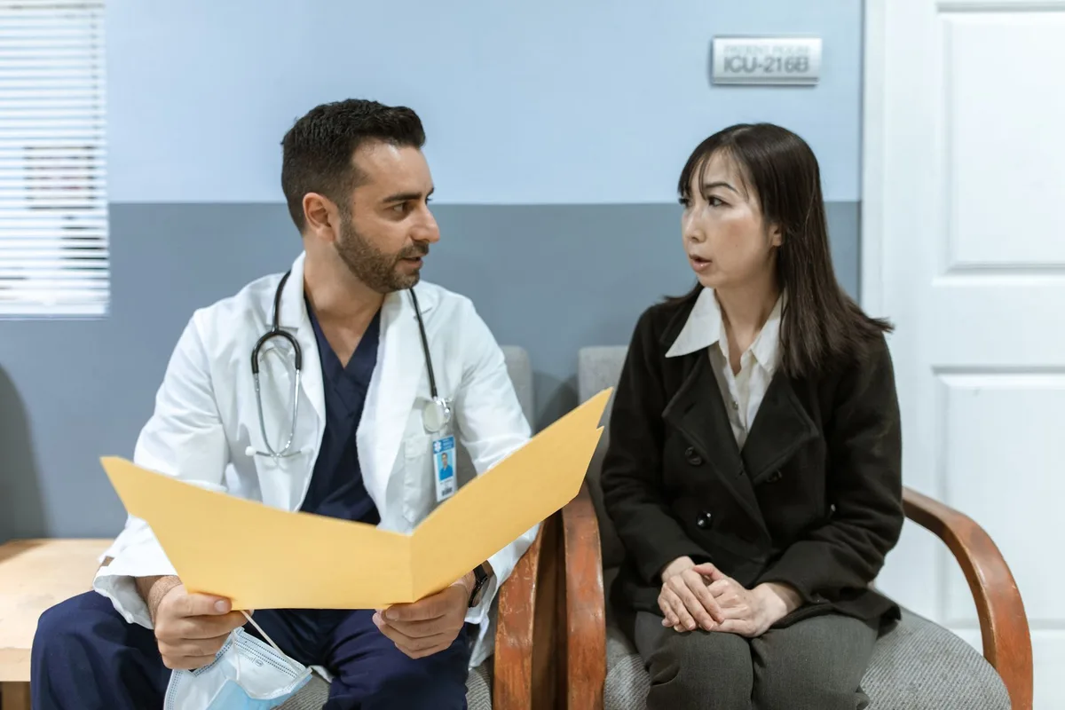 Une femme en consultation avec un praticien discutant de son traitement hormonal et de ses symptômes.