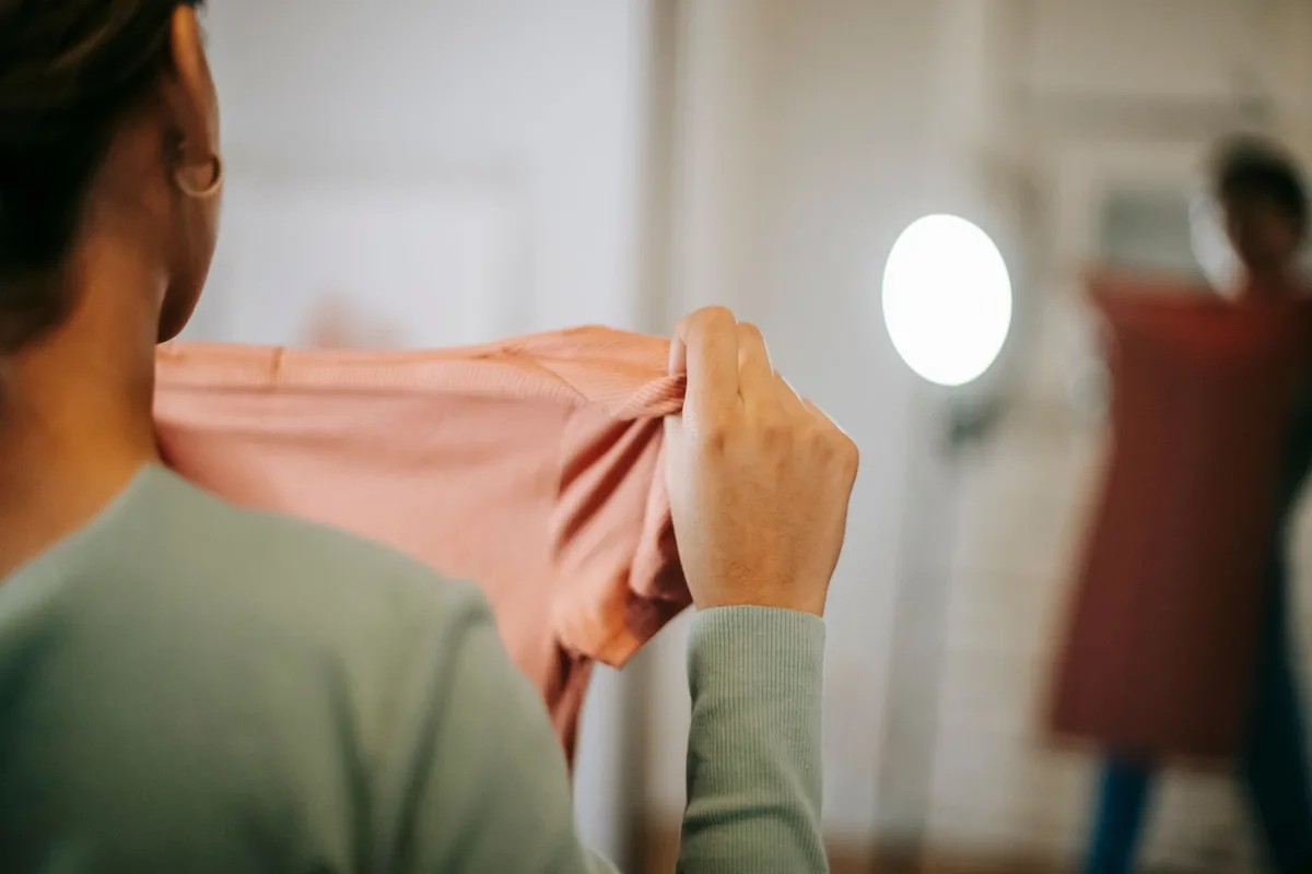 Femme essayant différentes couleurs et matières de trench court pour trouver la bonne teinte