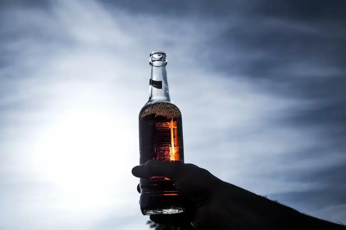 Mains anonymes appliquant du sérum près d'un flacon sur une vasque baignée de lumière