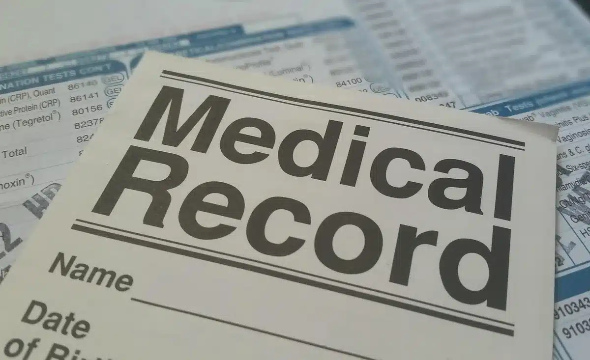 Personne organisant ses documents médicaux et sa liste de médicaments avant une consultation
