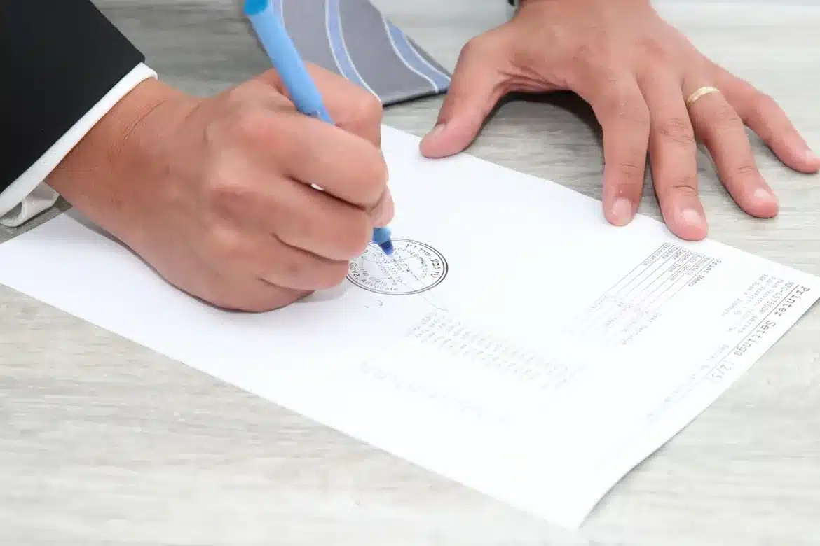Mains tenant des dossiers médicaux et un stéthoscope sur une table près d'une fenêtre en journée