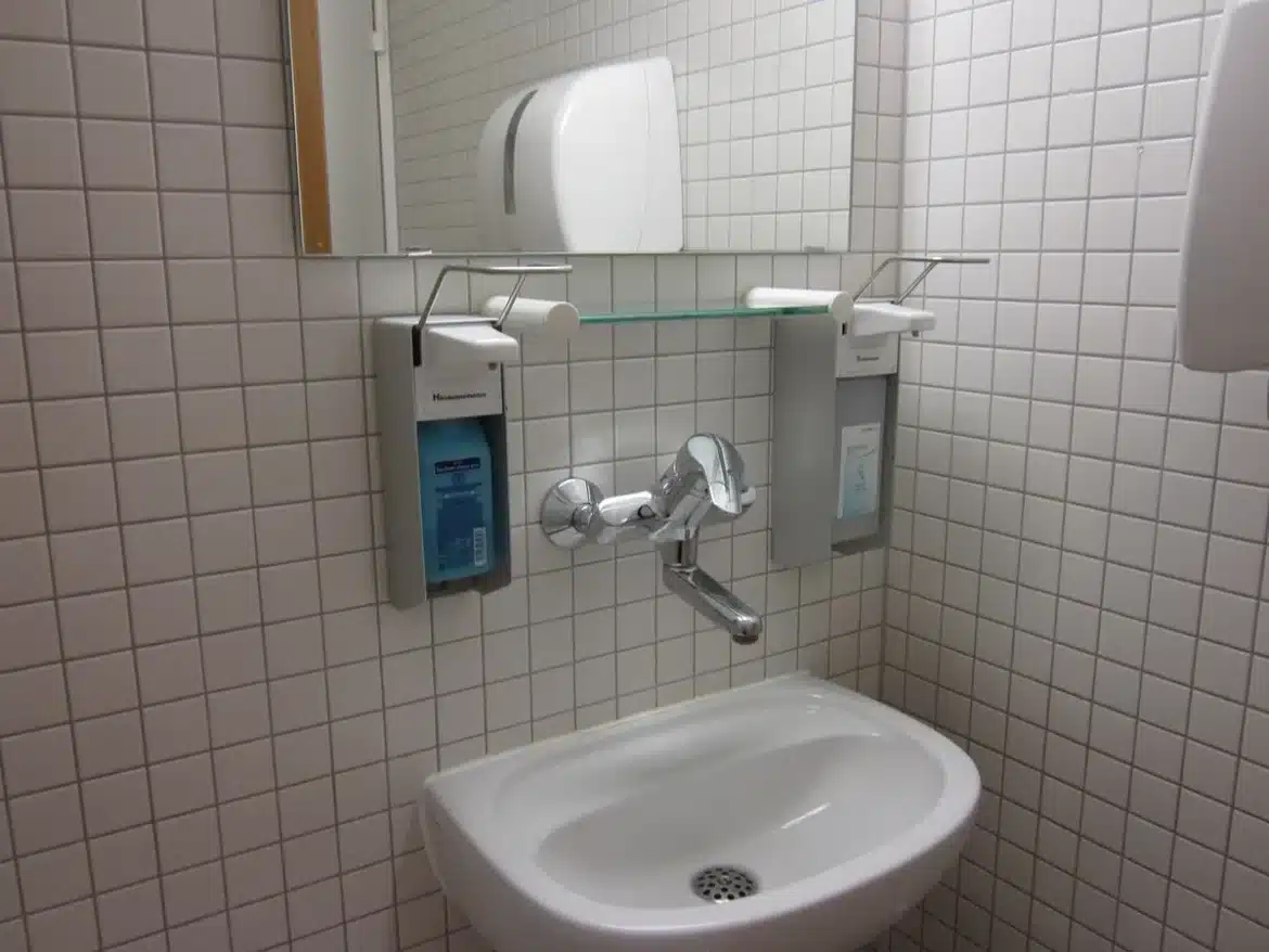 Personne se rinçant la bouche à l'eau tiède au-dessus d'un lavabo