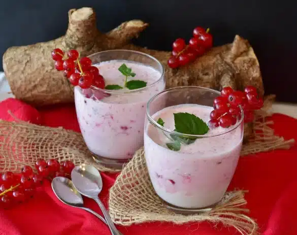 Shaker de protéine sur une table de cuisine en plein jour, avec fruits et haltères flous