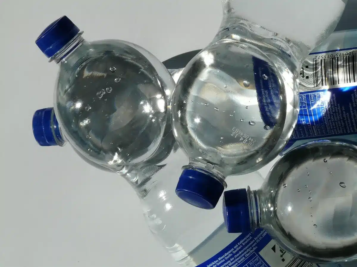 Flacon de sérum à l'acide hyaluronique posé près d'une serviette au soleil