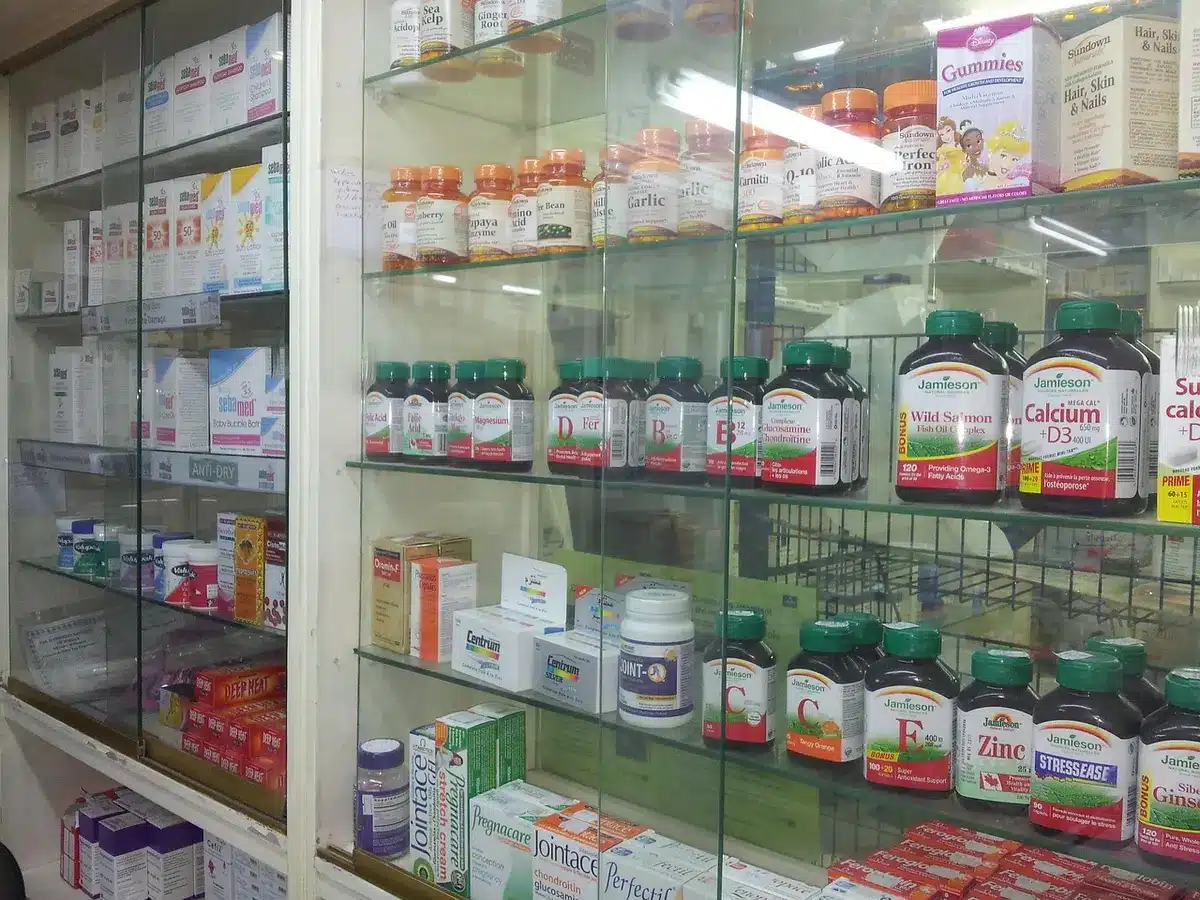 Main prenant un gummy près d'un bocal de compléments